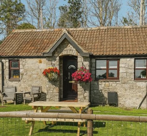 Gardeners Rest Cottage, a snug stone cottage with hanging baskets at Norton Court Farm