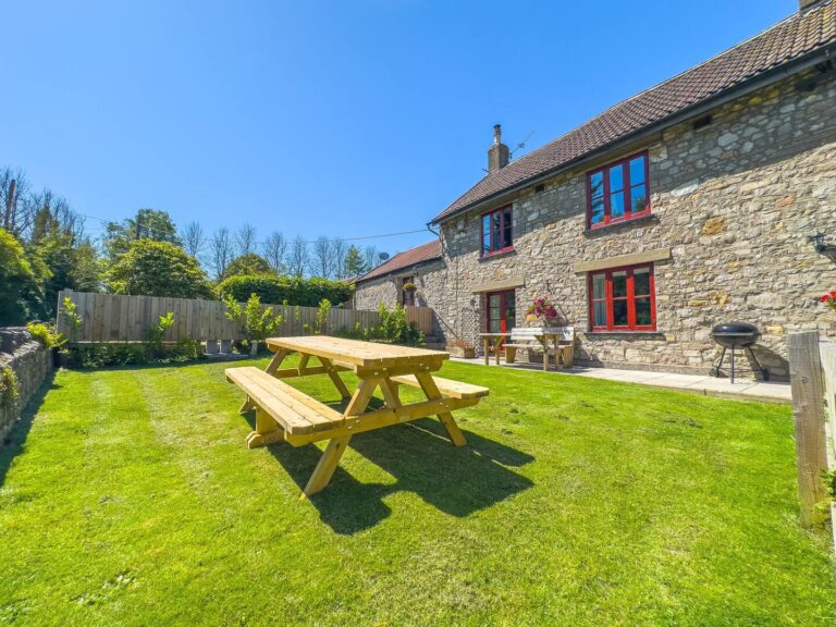 Garden with large picnic bench, BBQ, enclosed for dogs at Norton Court Cottage – dog-friendly holiday cottage in Kewstoke, Weston-super-Mare
